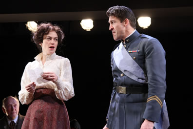 Beatrice holds a letter and looks amusingly at Benedick in uniform, who looks pained at the revelation in the letter